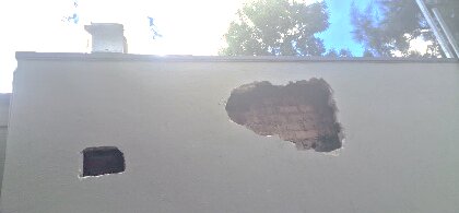 Two bee entry holes in an exterior wall under the roofline